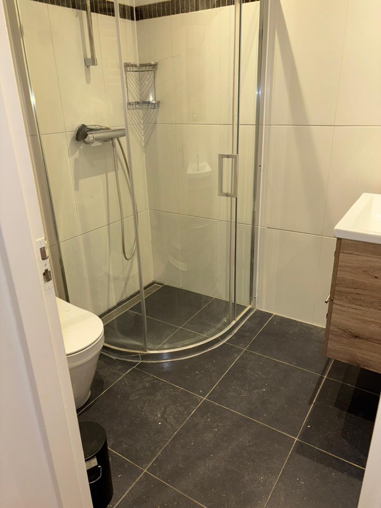 Schone badkamer met douchecabine en donkere tegelvloer